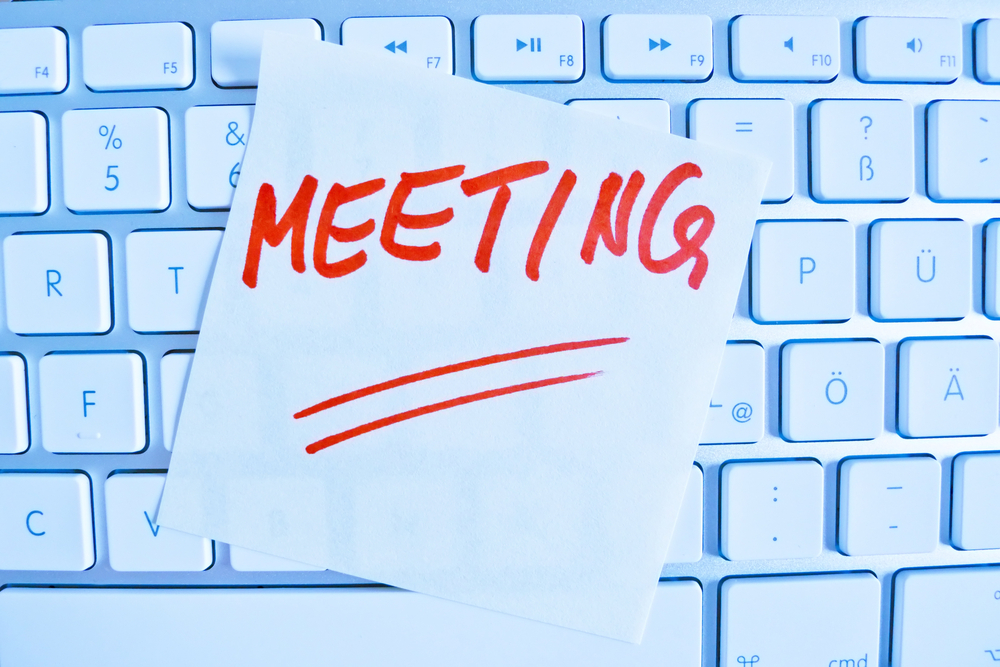 a memo is on the keyboard of a computer as a reminder: meeting
