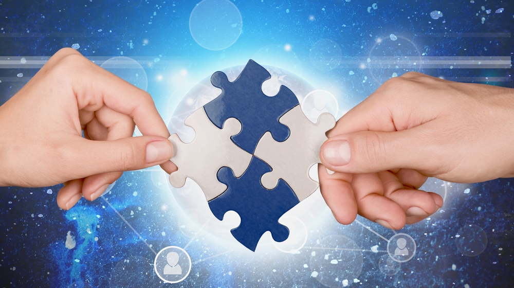 Two hands joining jigsaw pieces together.