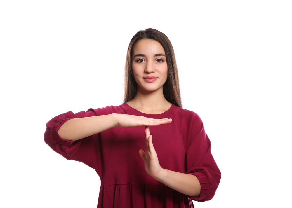 Photo of Woman showing TIME OUT gesture in sign language on white background