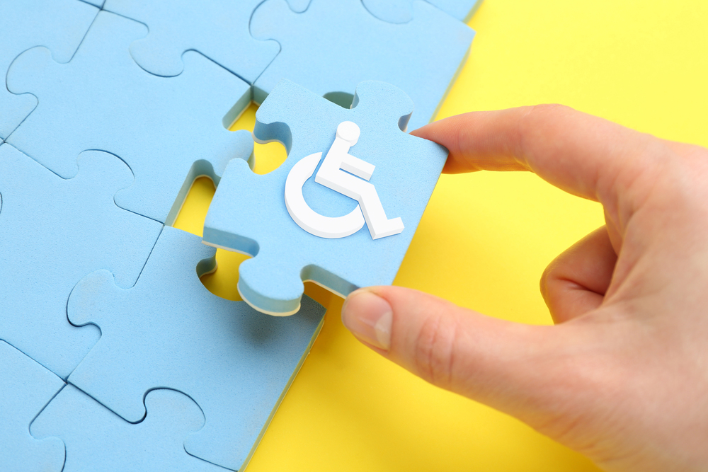 Reasonable Adjustments Woman putting light blue puzzle with international symbol of access together, 