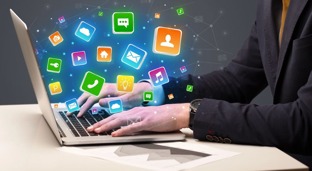 Person typing on a laptop with icons of different tools floating above.