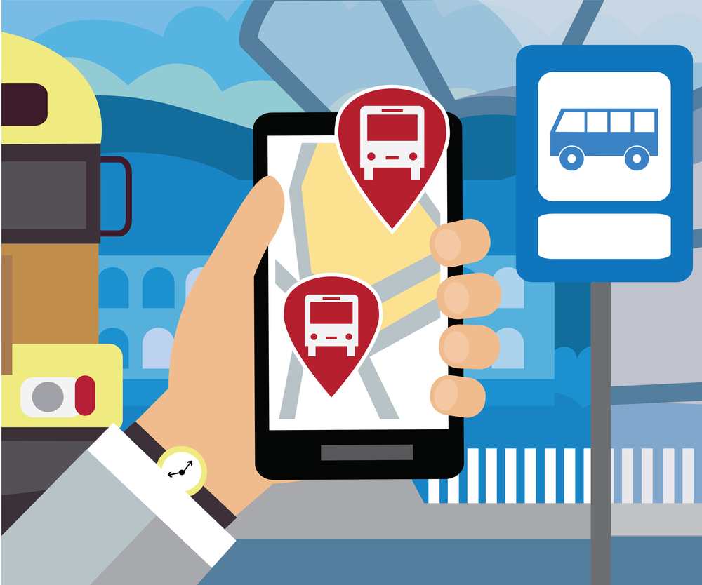 Accessible Digital Tools on a mobile phones is being held up by a person standing beside a bus stop.