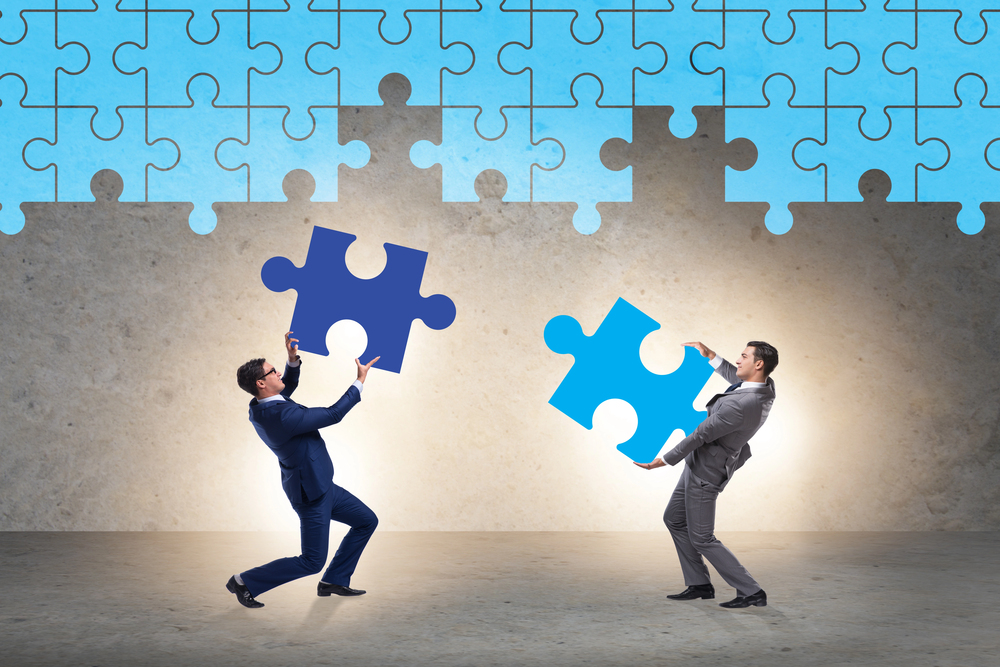 Two men are working together to do a puzzle incorporating digital inclusion and digital accessibility standards.