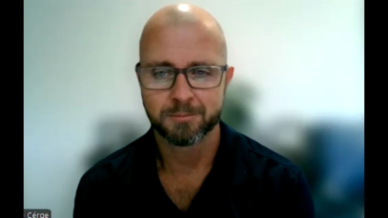 Chris Kerrisk is wearing black framed glasses and a button up shirt.