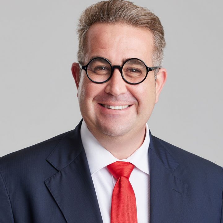 Frank Paolino is wearing a black suit and red tie.
