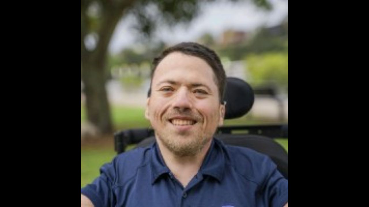 Mark Warren is sitting in his wheelchair in a park.