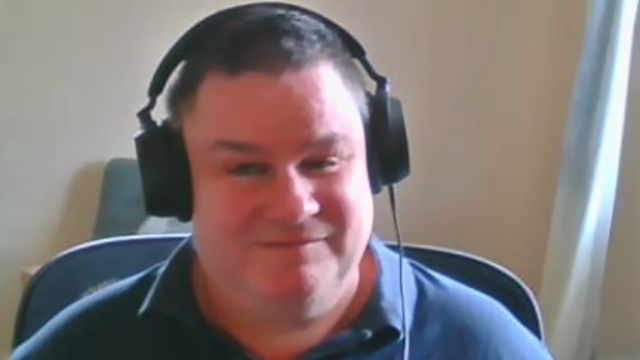 Paul Price is sitting in an office and is wearing headphones.