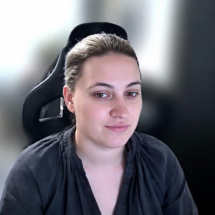 Hannah is sitting in an office and smiling.