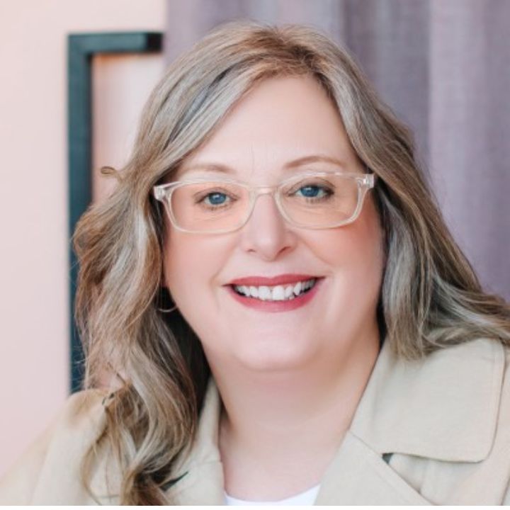 Sandra Muller has long fair hair and is sitting in an offic.e